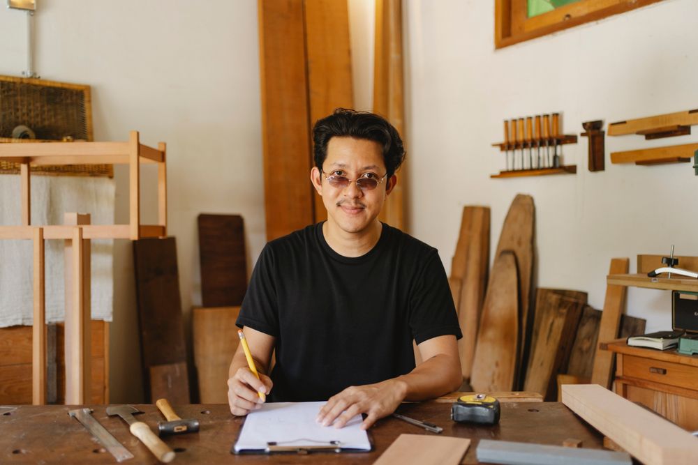 Carpintero sonriendo en su taller rodeado de madera